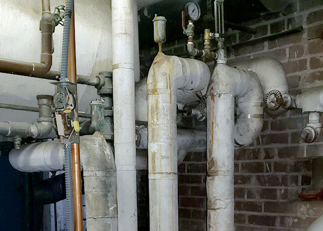 Pipes covered in white asbestos insulation