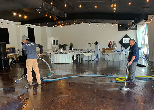 People cleaning a stained concrete restaurant floor
