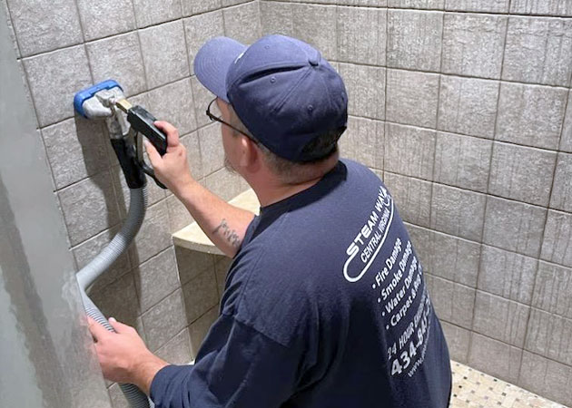 A man cleaning tile and grout in a shower