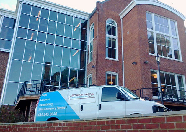 A van in front of a large brick and glass building