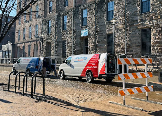 Two vans parked on a street in front of a stone building